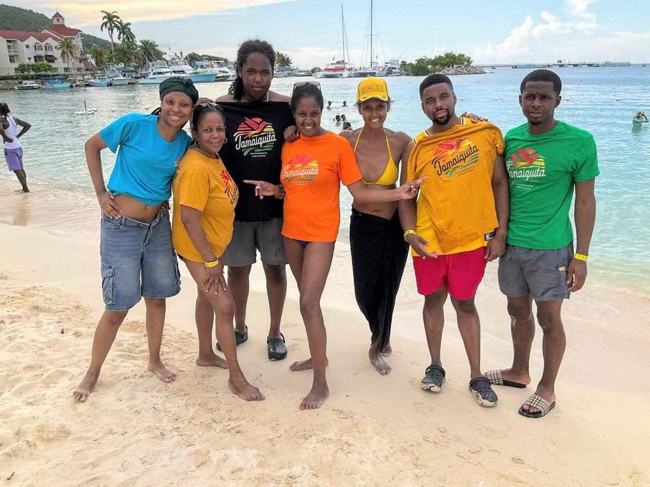 Familia Jamaiquita usando camisetas de la marca en una playa jamaiquina